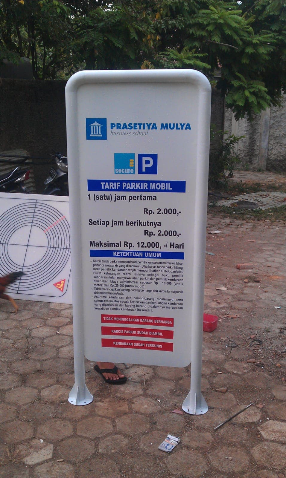 Papan informasi parkir putih dengan simbol P dan teks aturan