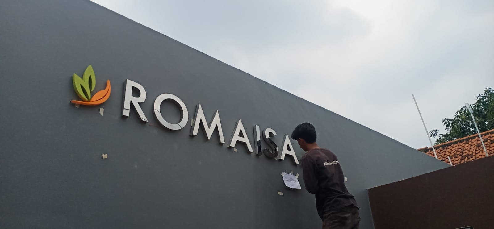 Pemasangan huruf timbul Romaisa pada dinding fasad luar ruang